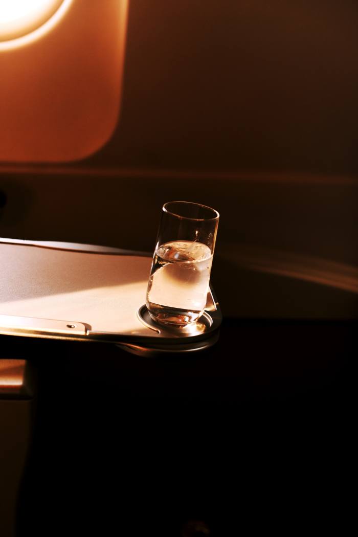 A glass of water on a sleek airline tray-table