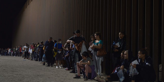 Migrants line up as they wait to be processed by US Border Patrol after illegally crossing the US-Mexico border in Yuma, Arizona.