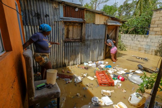 Two women walk through stagnant water in their homes caused...