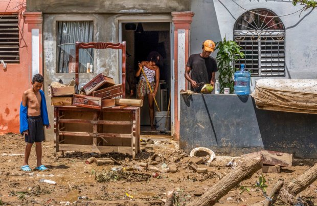 Neighbors work to recover their belongings after the flooding caused...