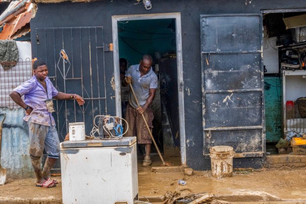 Neighbors work to recover their belongings from the flooding caused...