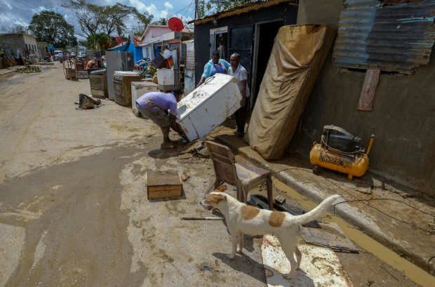 Neighbors work to recover their belongings from the flooding caused...