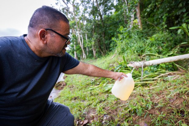 A man collects spring water from a mountain in Cayey,...