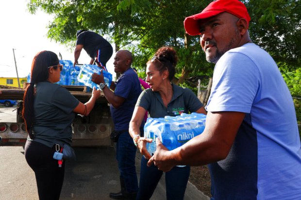 A man collects donated water bottles for drinking after Hurricane...
